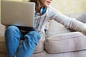 Teenage girl with laptop on sofa