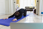 Woman practicing yoga online at home