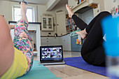 Women exercising online at laptop on kitchen floor