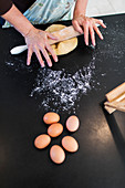 Woman rolling dough on kitchen counter