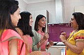 Happy Indian women in saris talking in kitchen