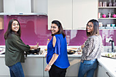 Portrait happy Indian sisters cooking food in kitchen