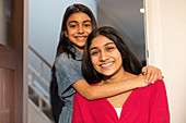 Portrait happy sisters hugging in doorway