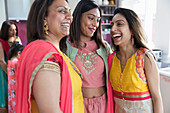 Happy Indian sisters in saris laughing in kitchen