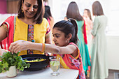 Indian mother and daughter in saris cooking with fresh herbs