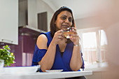 Portrait confident woman drinking tea in kitchen