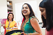 Happy Indian woman in sari preparing food with family