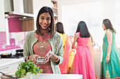Happy Indian woman in sari and bind cooking food in kitchen