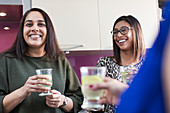 Happy women drinking in kitchen