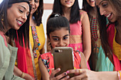 Indian women and girls in saris and bindis using smart phone