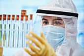 Female scientist in clean suit examining test tubes