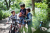 Mother and sons drinking water on bike ride in sunny park