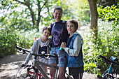 Happy mother and sons enjoying bike ride in sunny park