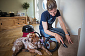 Woman with dog vacuuming carpet on stairs