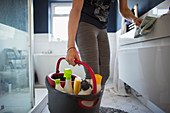 Woman with bucket of cleaners cleaning bathroom