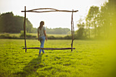 Branch frame over woman walking in idyllic sunny grass field