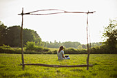 Branch frame over young woman using laptop in grass field