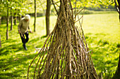 Senior woman gathering branches for teepee in woodland
