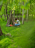 Woman making branch teepee in woodland