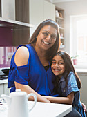 Portrait happy mother and daughter hugging in kitchen