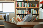 Man relaxing, reading book in living room