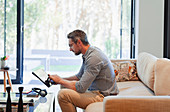 Man using digital tablet on living room sofa