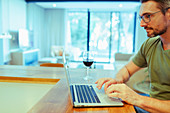 Man using laptop and drinking wine