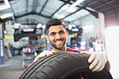 Portrait confident male mechanic with tire