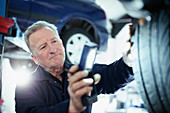 Male mechanic with flashlight examining tire