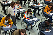Teacher supervising students taking exam at tables