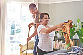 Mature couple folding clothes and sweeping at home