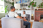 Couple talking and reading on living room sofa