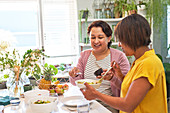 Women friends eating salad in kitchen