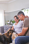 Affectionate couple petting dogs in living room