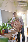 Affectionate mature couple watering houseplants