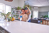 Mature couple hugging and cleaning kitchen island