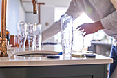 Man washing glass bottles at kitchen sink