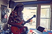 Male musician with laptop playing guitar