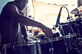 Male drummer adjusting drums in recording studio