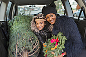 Mother and daughter with Christmas tree in car