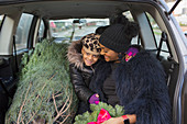 Mother and daughter in car with Christmas tree