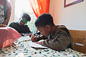 Boy writing Christmas cards at table