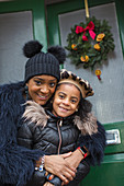 Mother and daughter hugging on front stoop