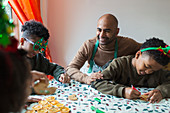 Happy father and sons decorating Christmas cookies