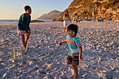 Family playing cricket on sunny beach