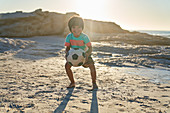 Portrait boy playing with soccer ball on beach