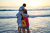 Happy family hugging in ocean surf