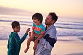 Happy father and sons playing on ocean beach