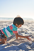 Boy playing in sand on sunny summer beach