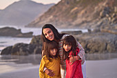 Portrait happy mother and daughters on beach